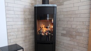 A black wood-burning stove with a glass door, set against a tiled wall. - Beautiful apartment for 4 guests with WIFI, TV, terrace and panoramic view (Evolène)