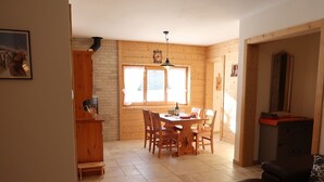 A cozy room with a wooden dining table, chairs, a sofa, and a fireplace. - Beautiful apartment for 4 guests with WIFI, TV, terrace and panoramic view (Evolène)