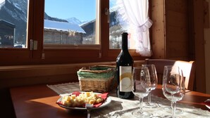 A wooden cabin with a table set for a meal, a bottle of wine, and glasses. - Beautiful apartment for 4 guests with WIFI, TV, terrace and panoramic view (Evolène)