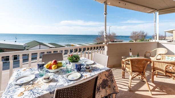Ein Balkon mit einem Esstisch, mit Blick auf ein Gewässer.