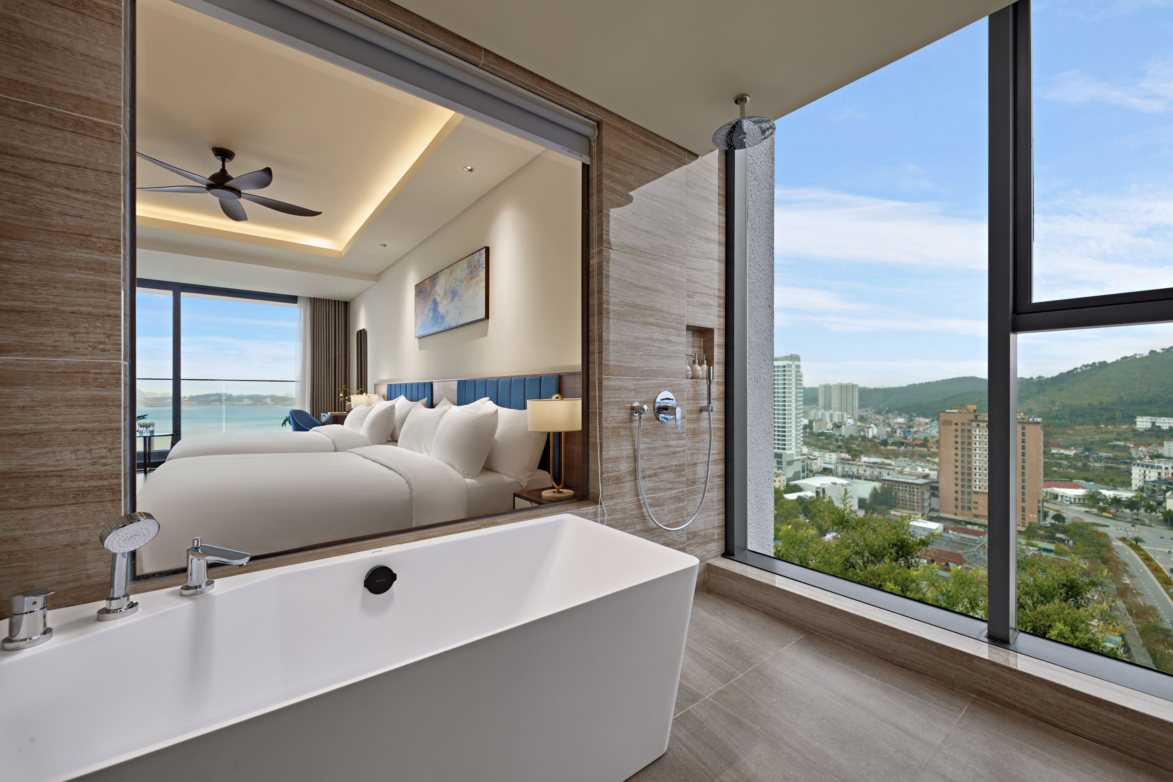 Ein modernes Badezimmer mit einer großen Badewanne, einer Dusche und Blick auf die Stadt durch große Fenster.