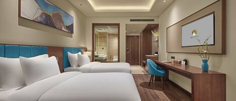 A hotel room with two beds, a desk, a chair, a ceiling fan, and a large abstract painting on the wall.