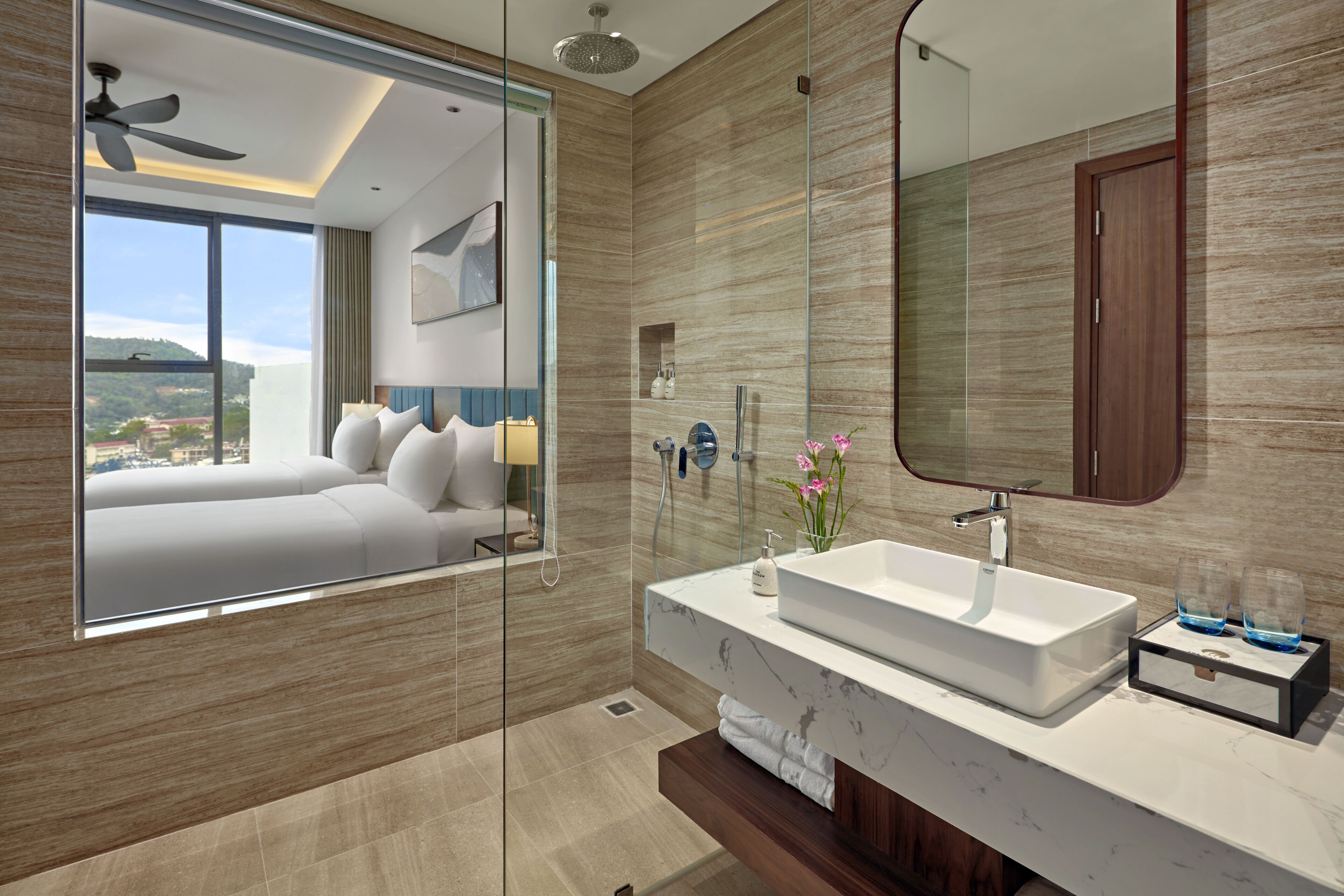 A modern bathroom with a large mirror, a white sink, and a glass shower enclosure.