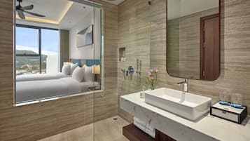 A modern bathroom with a large mirror, a white sink, and a glass shower enclosure.