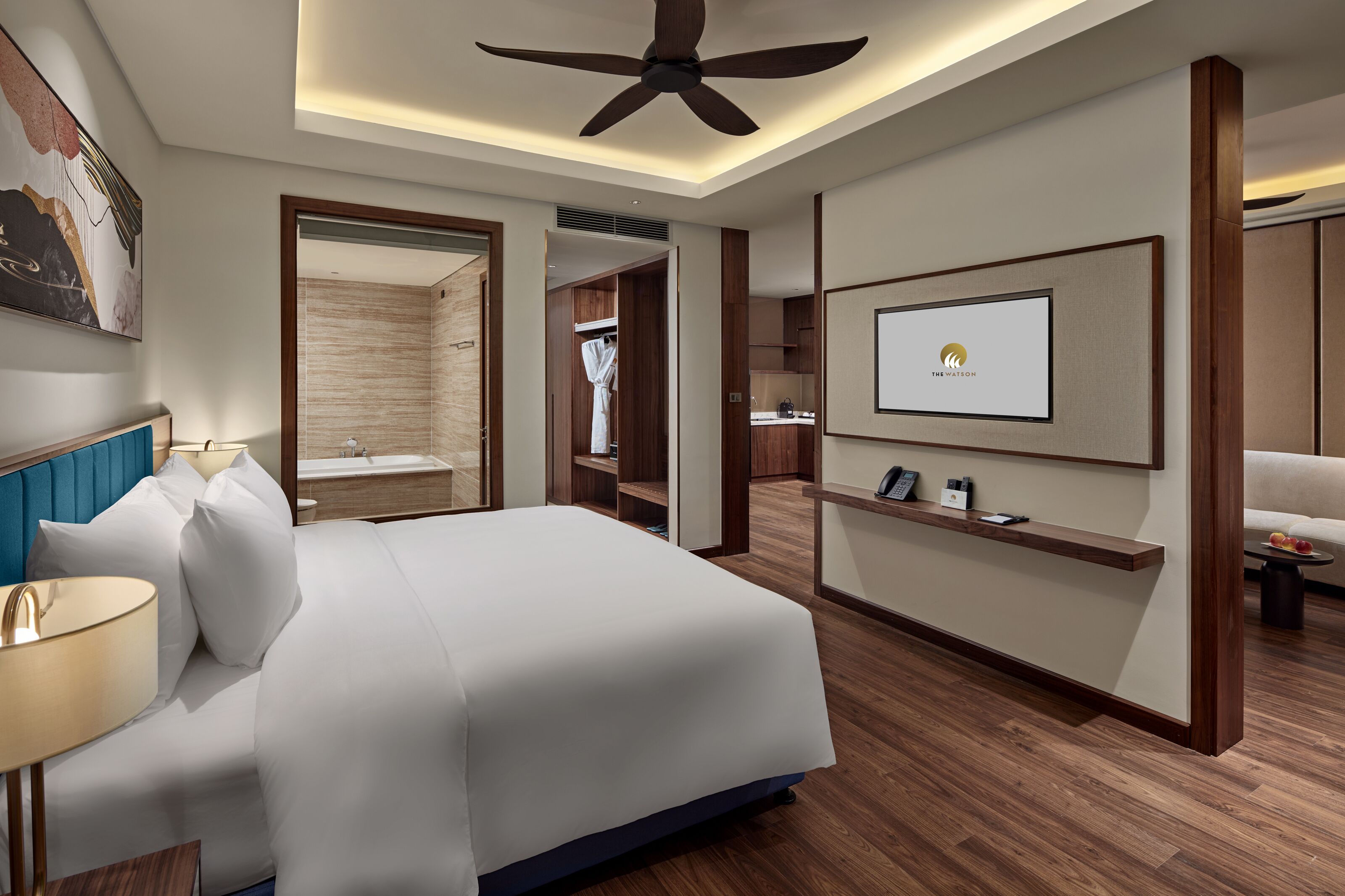 A modern hotel room with a large bed, a ceiling fan, a mounted TV, and a wooden floor.