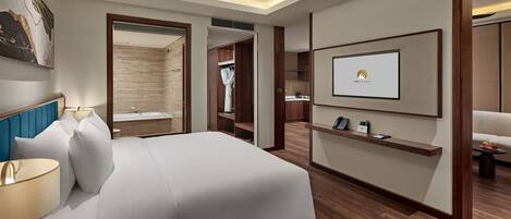 A modern hotel room with a large bed, a ceiling fan, a mounted TV, and a wooden floor.