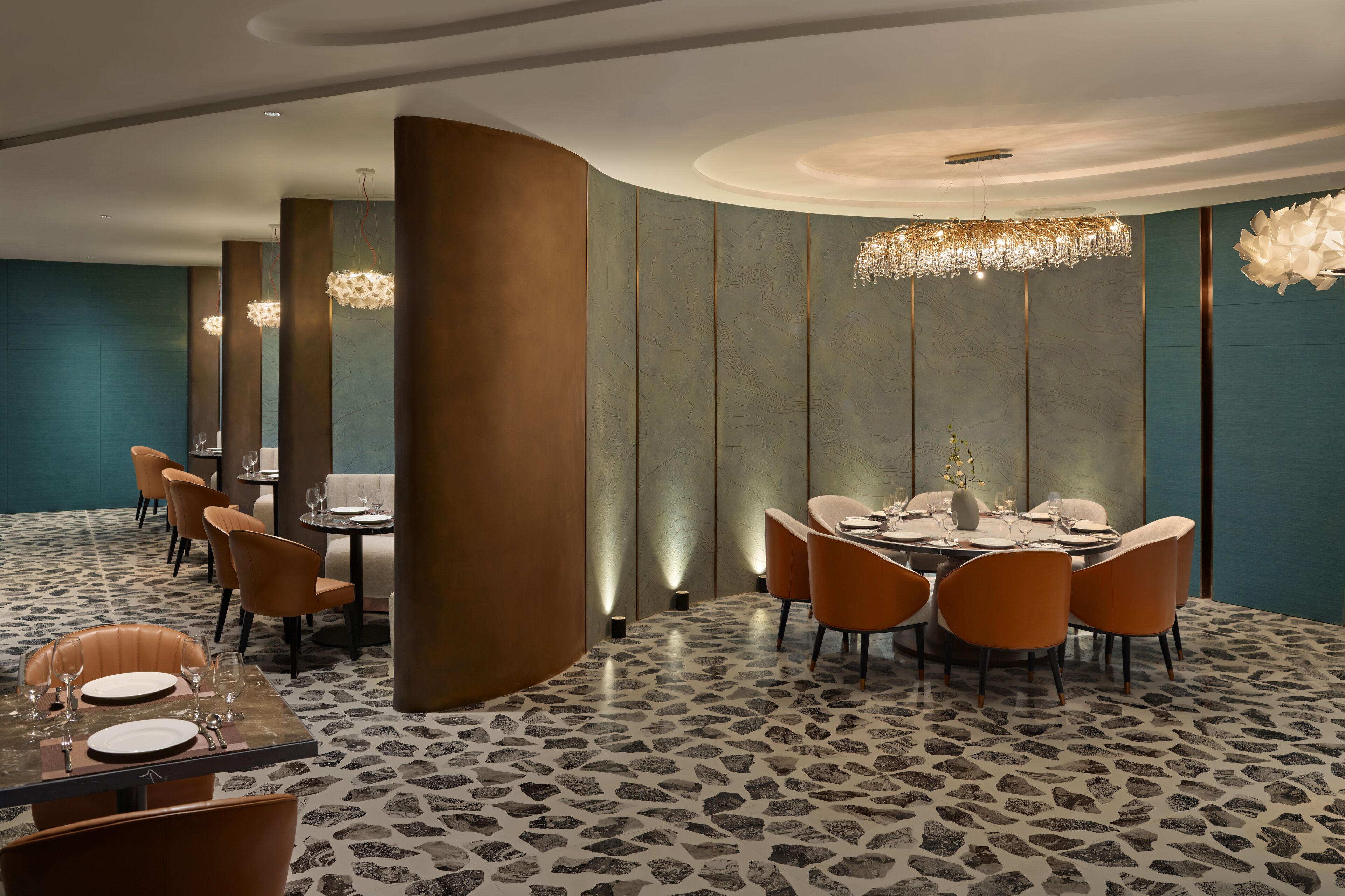 A modern dining area with a round table set for four, surrounded by orange chairs.