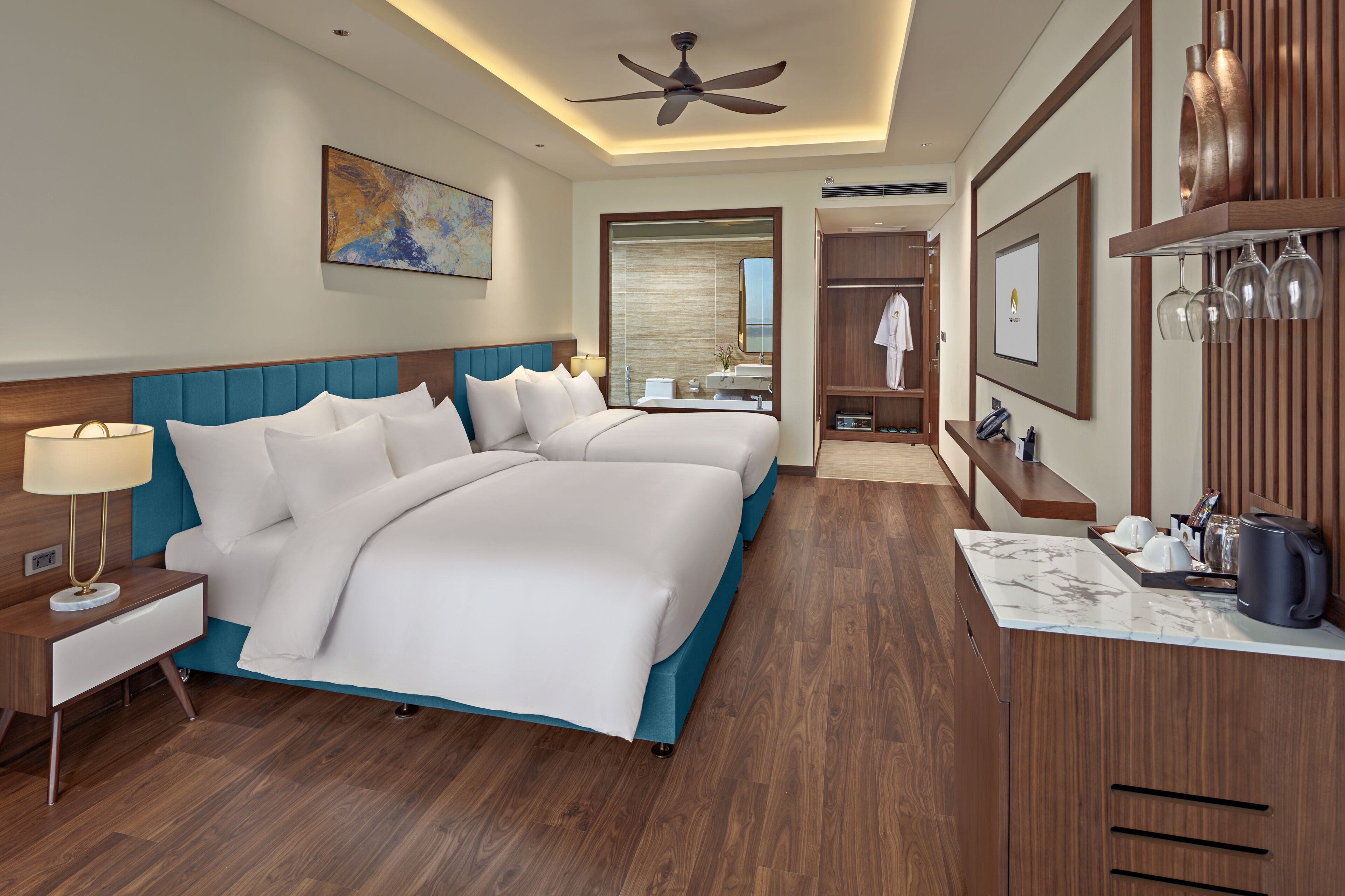 A hotel room with a large bed, a desk, a mirror, and a wardrobe.