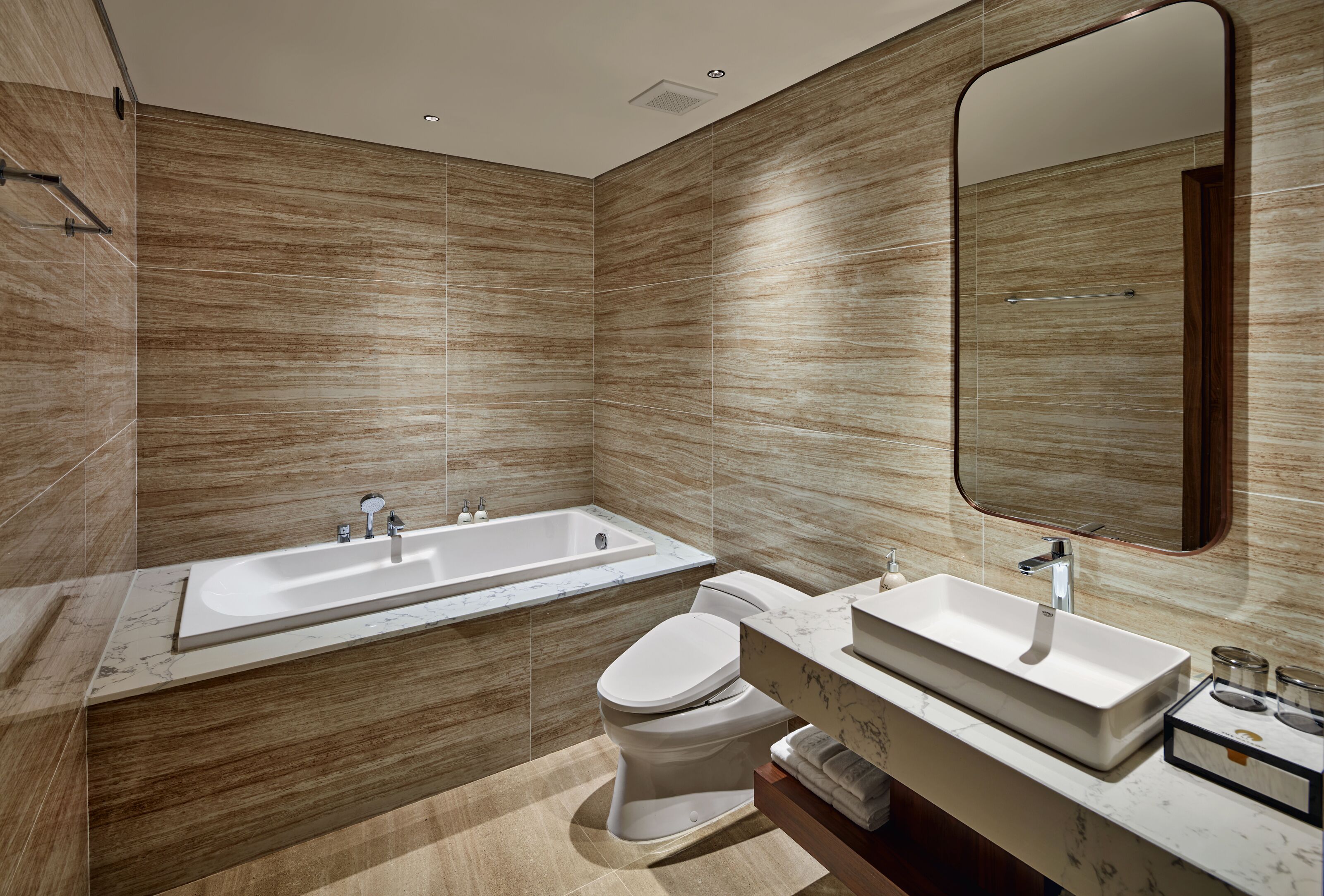 A modern bathroom with a bathtub, toilet, and two sinks.