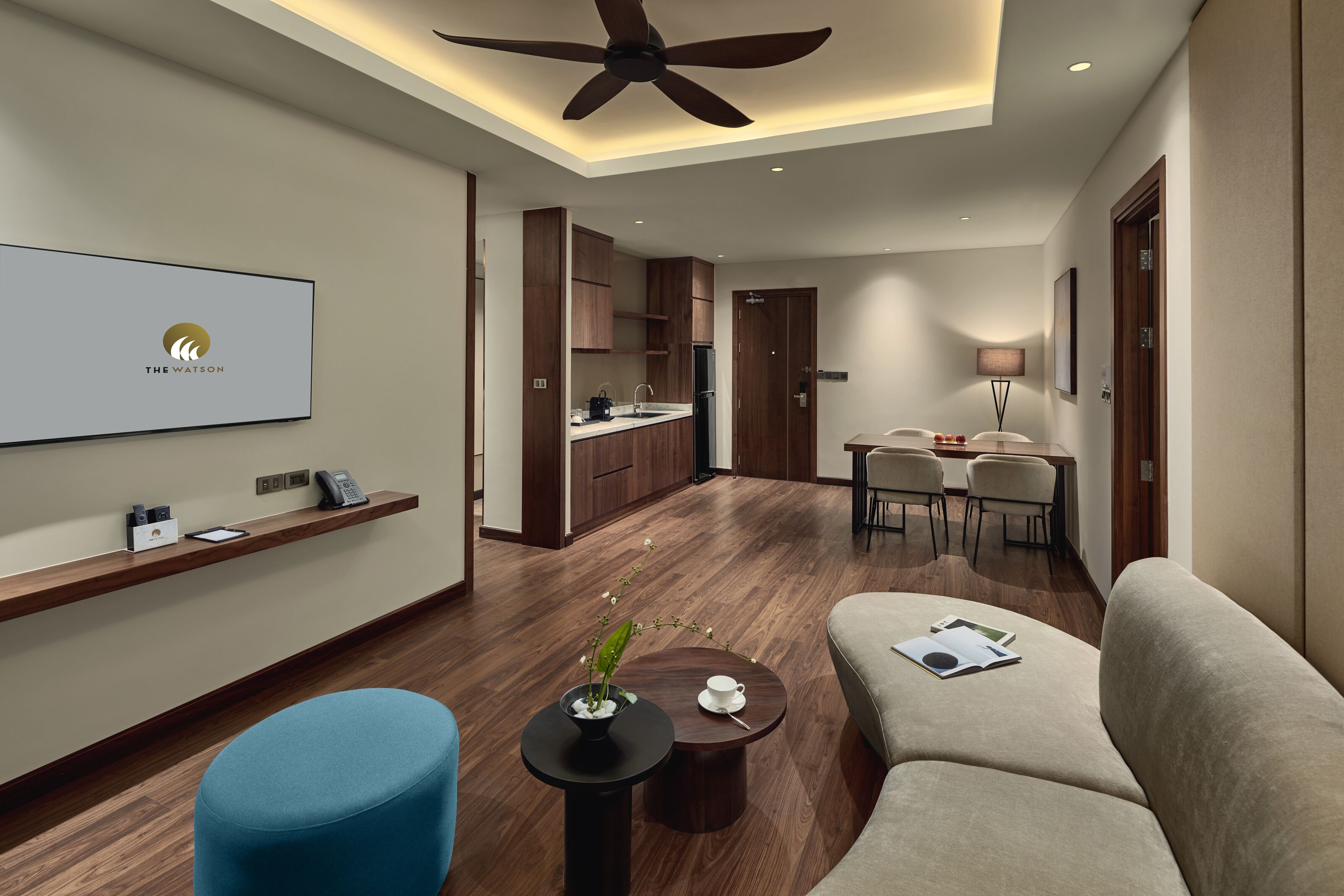 A modern hotel room with a living area, kitchenette, and a dining area.