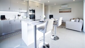 A modern kitchen with white cabinetry, a central island, and stainless steel appliances. - Nice apartment for 4 people with A/C, WIFI, pool, TV and balcony (Portimão)