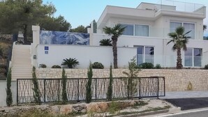 A modern two-story building with a stone facade, large windows, and a metal fence.