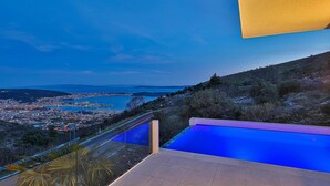 A pool with a view of a coastal town and a body of water.