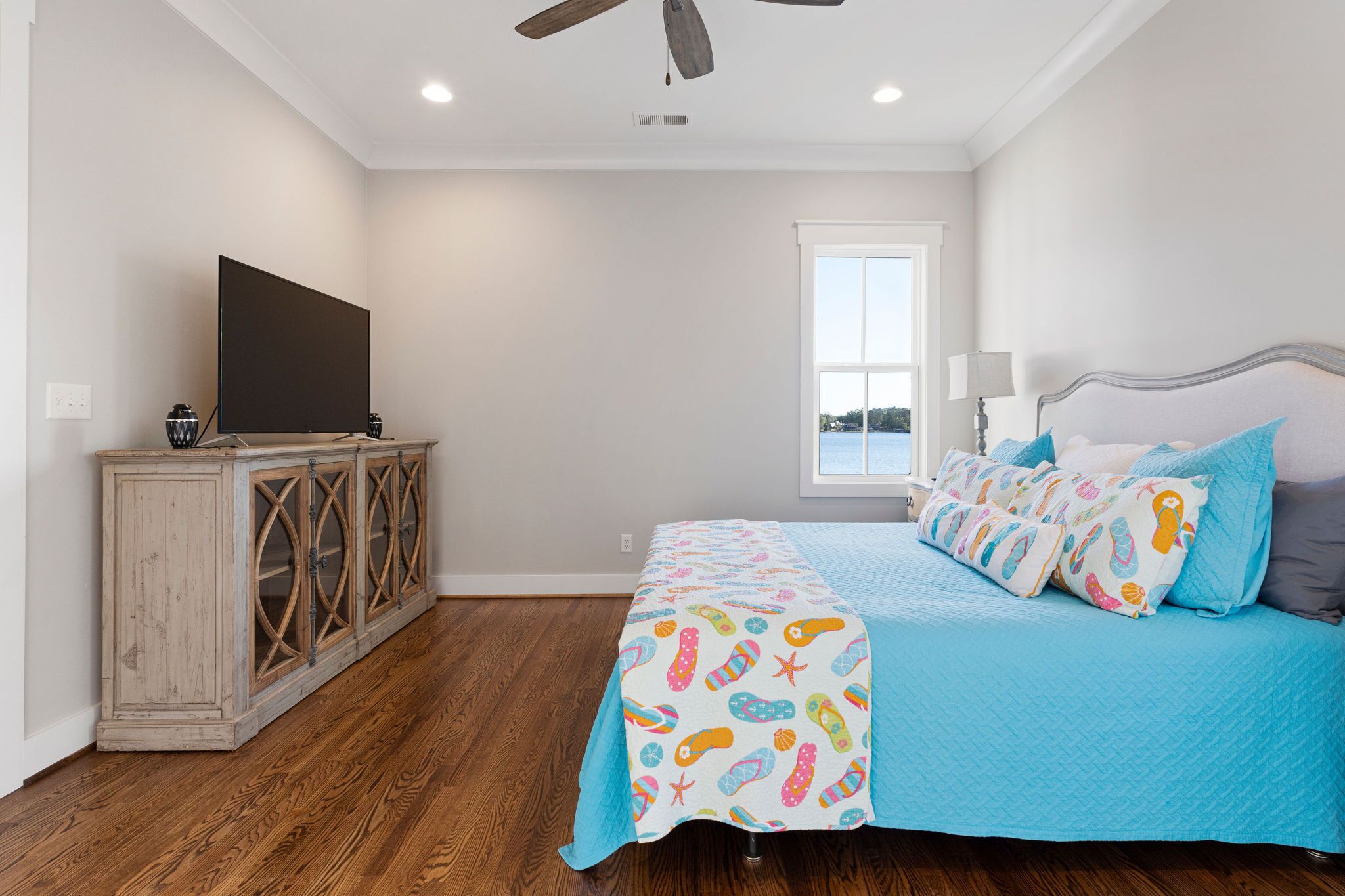 A bedroom with a bed, a television, a cabinet, and a window.