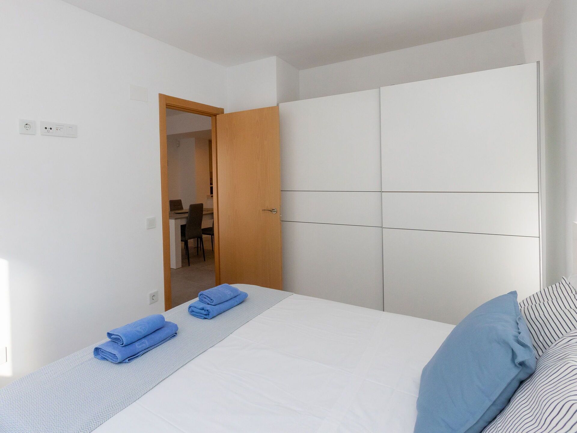 A bedroom with a bed, a wardrobe, and a desk with a chair.
