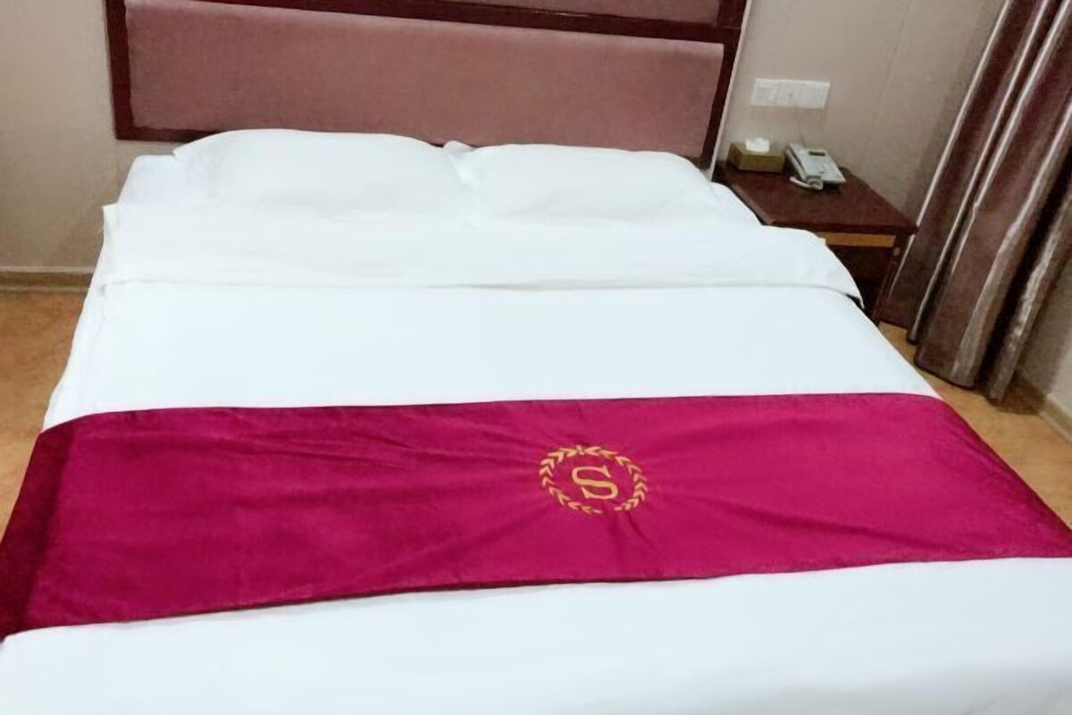 Una habitación de hotel con una cama, una mesita de noche y un teléfono.