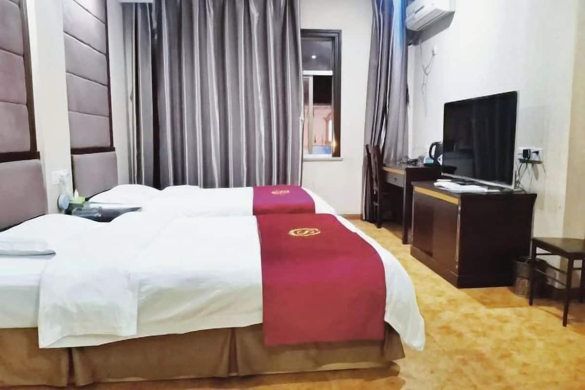 A hotel room with a large bed, a desk with a laptop, and a television.