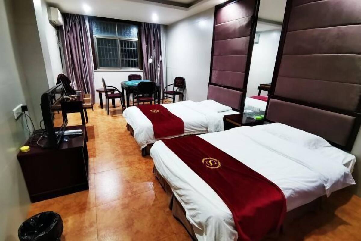 A hotel room with two beds, a desk, a chair, and a window with curtains.