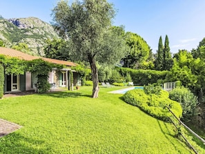 Une maison avec un jardin, une piscine et une montagne en arrière-plan.