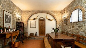A rustic cellar with stone walls, a wooden table, benches, and a wine rack. - Cosy apartment in villa for 4 people with WIFI, terrace, pets allowed and panoramic view (Greve In Chianti)
