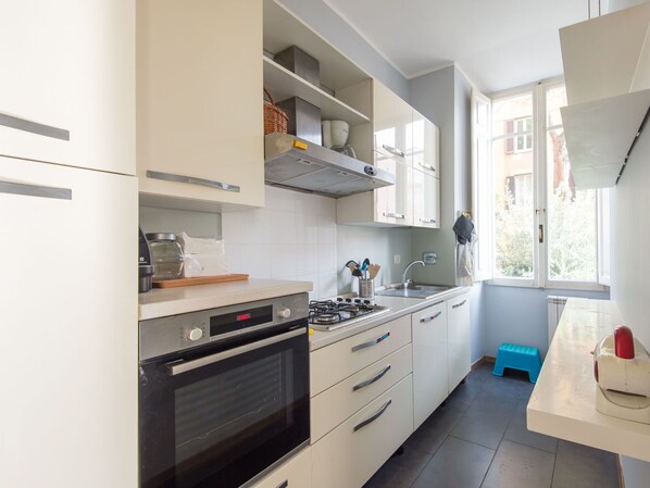 Una cocina moderna con armarios blancos, estufa a gas, horno y ventana que proporciona luz natural.