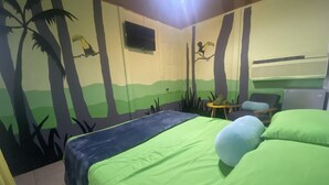 Una stanza con un letto, un tavolino, una sedia e una televisione.
