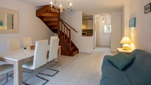 Een moderne woonkamer met een eethoek, een trap en een keuken.