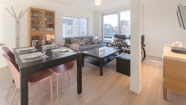 Una sala de estar moderna con comedor, un conjunto de sofás y un mueble de madera.