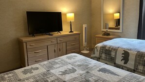 A hotel room with a TV on a dresser, two beds with patterned bedding, a standing fan, and a mirror on the wall. - Relax and unwind Townhome in Snow Ridge Village at Jack Frost mtn in the Poconos (Lake Harmony)