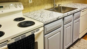 A kitchen with white cabinets, a granite countertop, a stainless steel sink, and a white stove. - Relax and unwind Townhome in Snow Ridge Village at Jack Frost mtn in the Poconos (Lake Harmony)