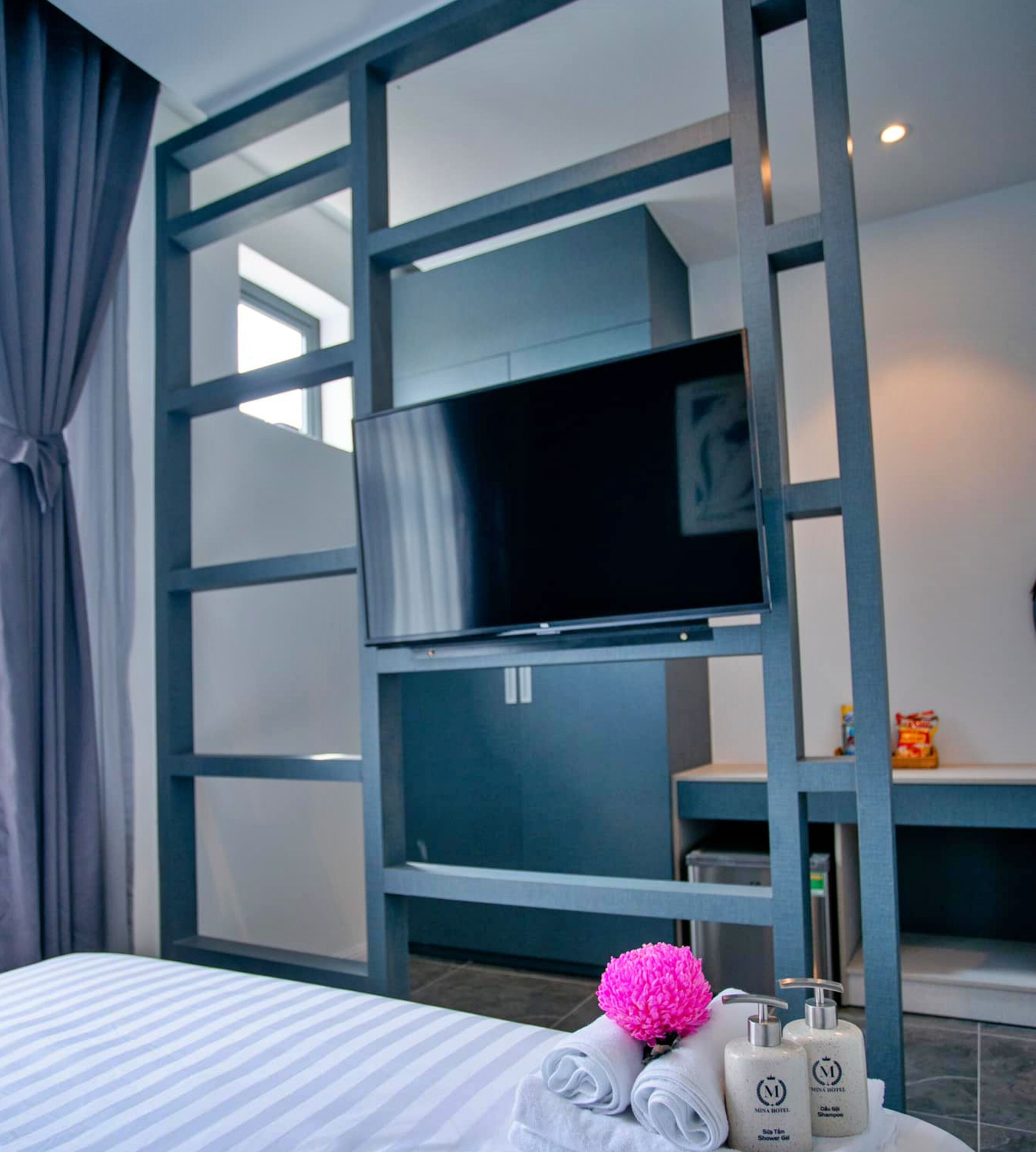 A hotel room with a bed, a television, and toiletries on a table.