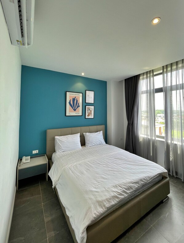 Una habitación de hotel con una cama grande, una mesita de noche con un teléfono y obras de arte en la pared.