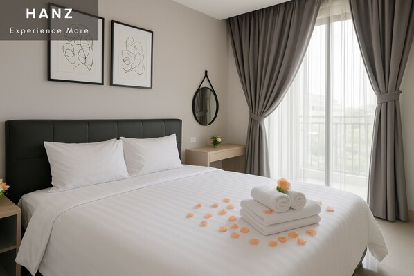 A hotel room with a large bed, a nightstand, a framed artwork, a mirror, and a window with curtains.