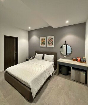 A modern bedroom with a large bed, bedside tables, a mirror, and a small refrigerator.