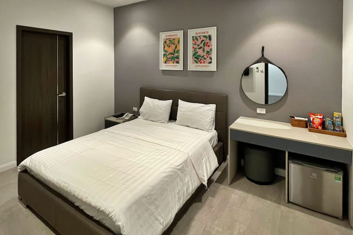Une chambre à coucher comprenant un lit, une table de chevet, un miroir et des œuvres d’art murales.