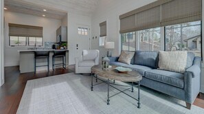 A modern living room with a sofa, coffee table, and kitchen area in the background.