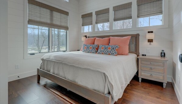 A bedroom with a large bed, a nightstand, and a window with blinds.