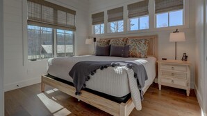 Een slaapkamer met een groot bed, twee nachtkastjes en een raam met jaloezieën.