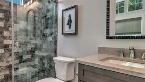 Une salle de bain avec une douche à parois de verre, des toilettes blanches et un meuble-lavabo avec un évier et un miroir.