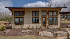 A modern two-story house with large windows and a stone foundation. - Golf and Riverfront Cottage | King Bed | Group Availability (Mineral Bluff)