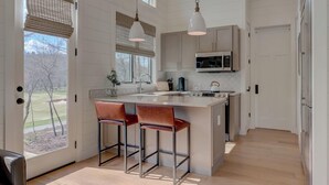 Een moderne keuken met een centraal eiland, roestvrijstalen apparatuur en uitzicht op de omgeving.