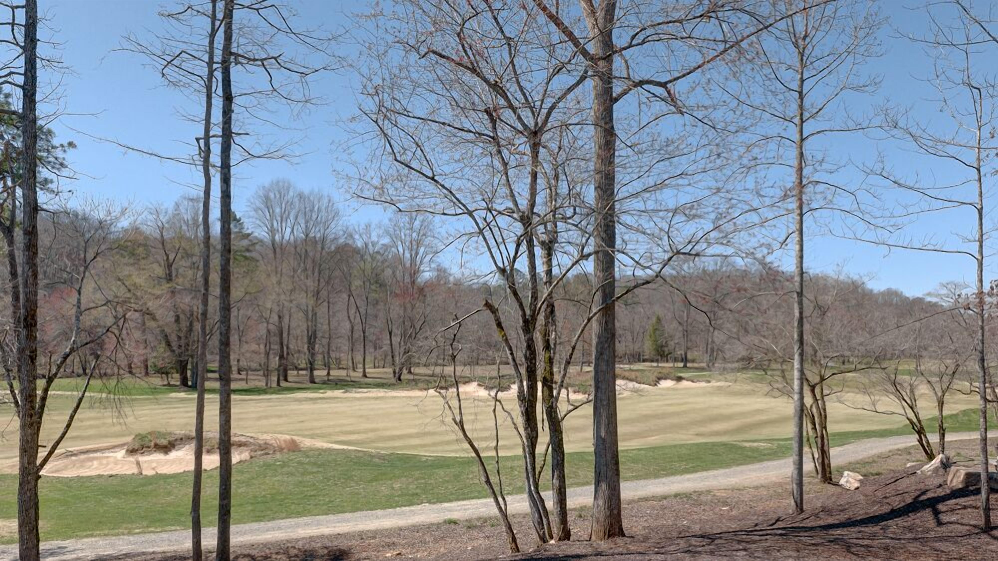 A golf course with sand bunkers and a clear sky.