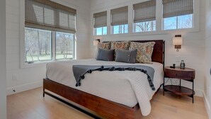 Una camera da letto con un letto grande, diverse finestre, un comodino e un tavolino.