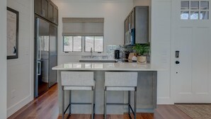 A modern kitchen with a central island, stainless steel appliances, and a window with blinds. - Golf and Riverfront Cottage | King Bed | Group Availability (Blue Ridge)