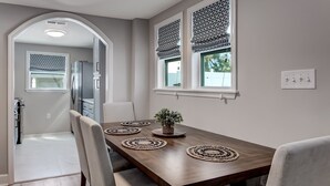 Un comedor con una mesa de madera, cuatro sillas y una planta en maceta.