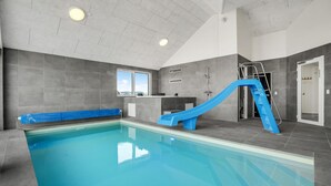 An indoor swimming pool with a blue slide, a window, and a shower area. - Nice home in Bogense with sauna (Bogense)