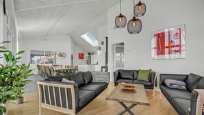 A modern living room with a dining area, a fireplace, and a large window. - Nice home in Bogense with sauna (Bogense)