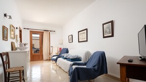 Un salon avec un canapé, une table en bois, un téléviseur et des tableaux encadrés accrochés au mur.