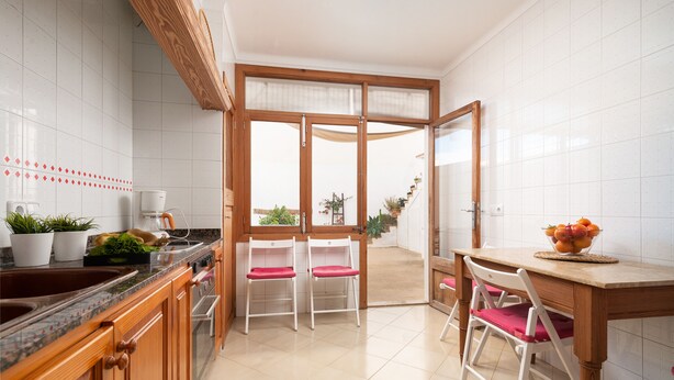 Une cuisine moderne avec des meubles en bois, un plan de travail en granit et un coin repas comprenant une table et des chaises en bois.