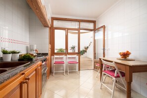 Une cuisine moderne avec des meubles en bois, un comptoir en granit et un coin repas comprenant une table et des chaises en bois.